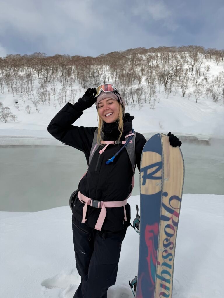 Snowboarder posing with her board in the snow