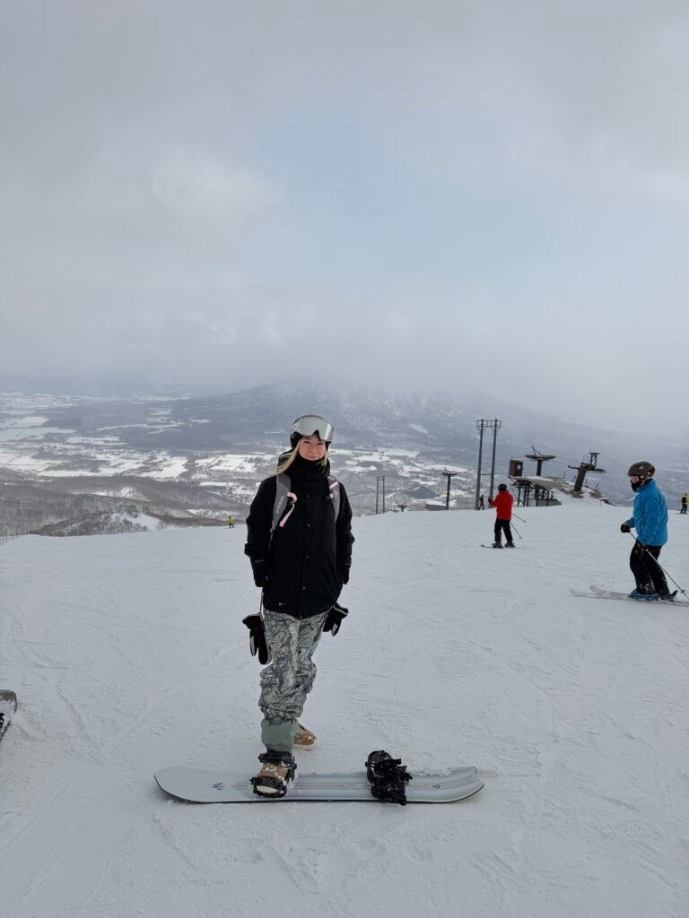 Snowboarder on a groomed run in Hokkaido with mountains behind