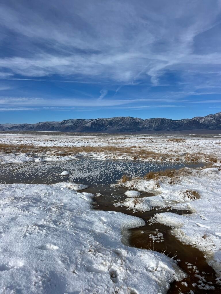 Snow around a hot spring under a stormy winter sky