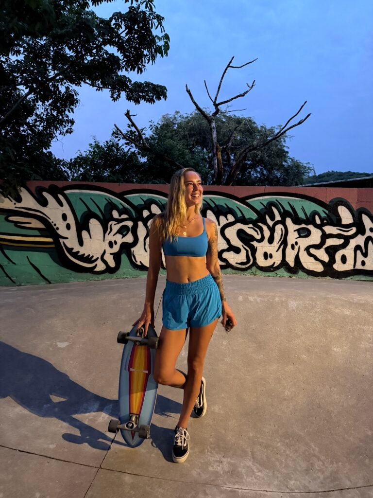 Holding a surfboard in my sports bra and running shorts in El Zonte