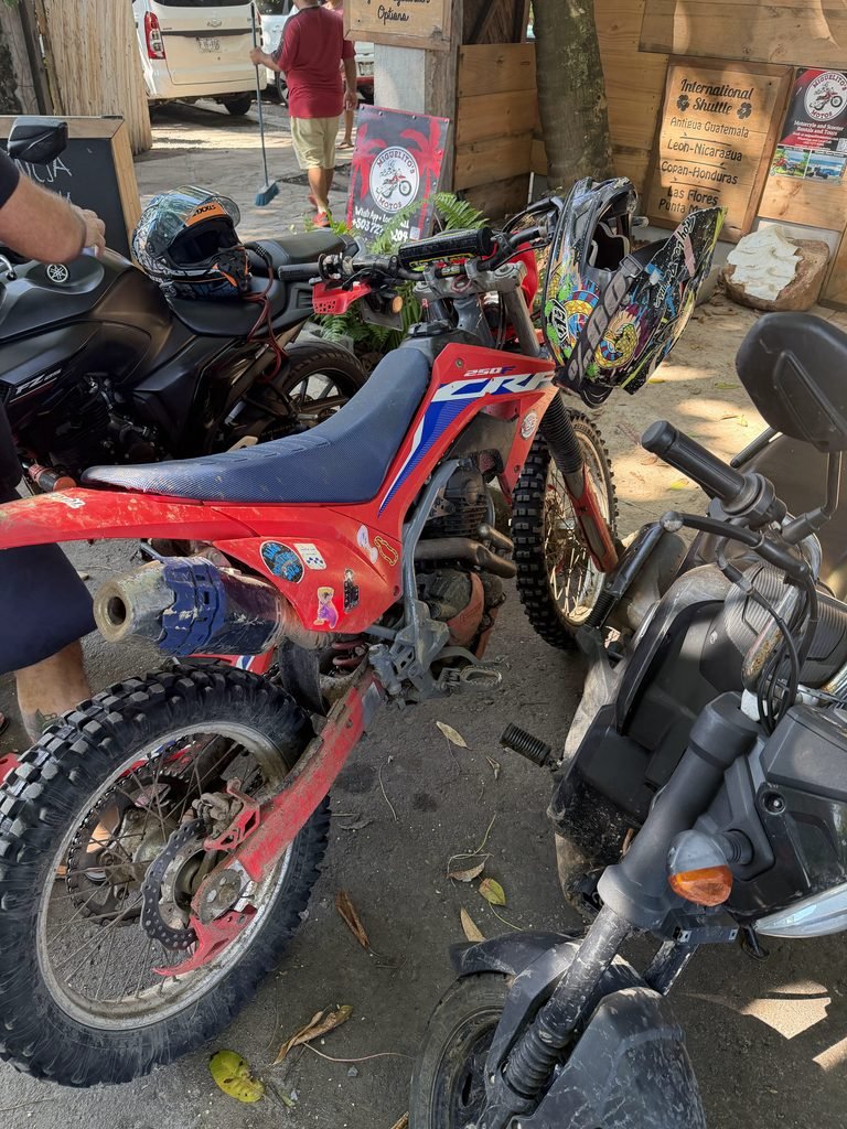 Red Honda dirt bike with a helmet on the handlebars, parked before the ride in El Zonte