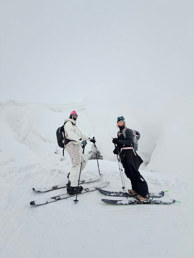 Two skiers stopped in the clouds near the top of Asahidake