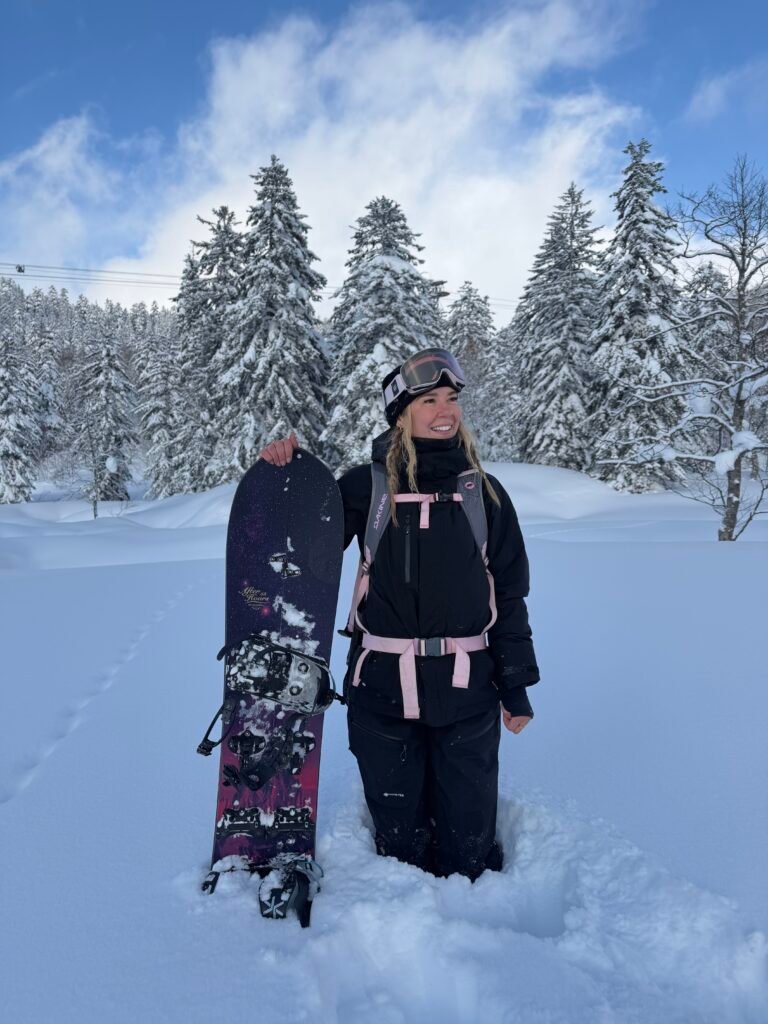 Standing with my snowboard under blue skies in Japan