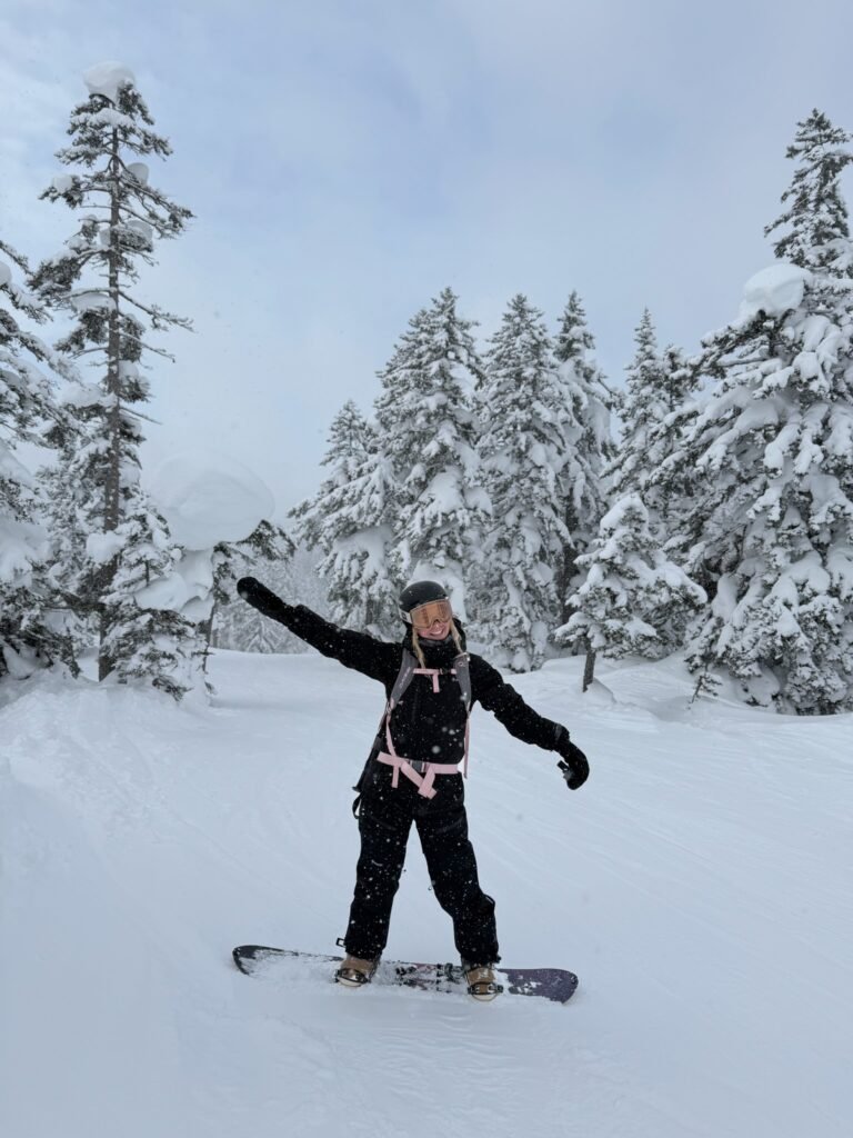 Snowboarding through snowy trees in Japan, arms out