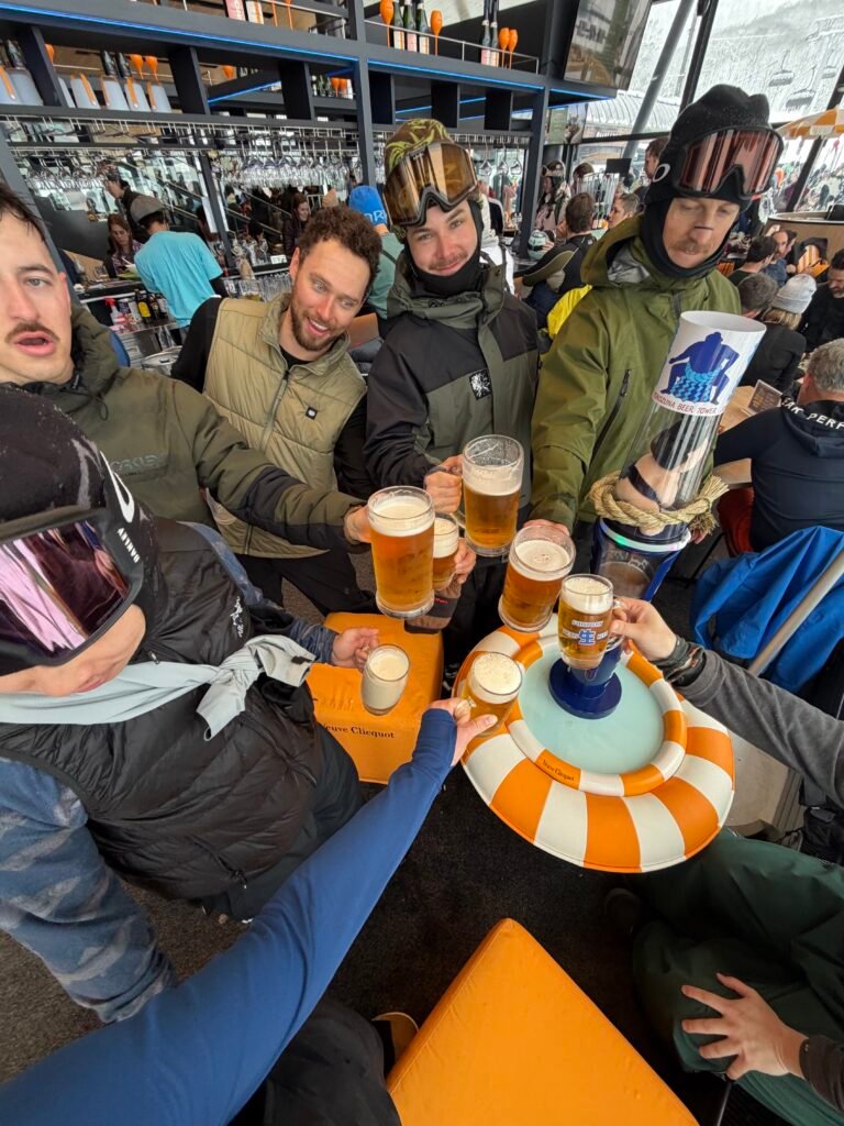 College ski club friends cheersing beers at lunch in Niseko