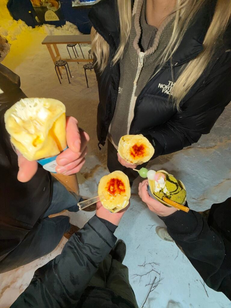 Friends holding up crepes on a snowy night in Niseko