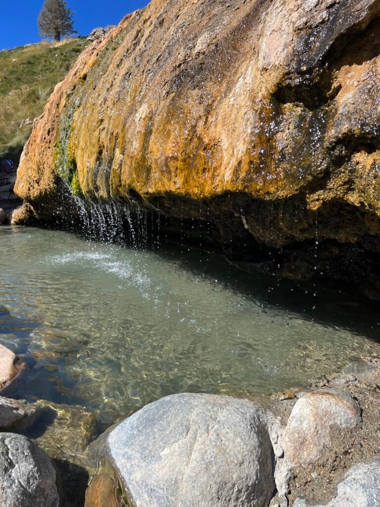 Creekside soaking pool under the mineral-stained rock at Buckeye Hot Springs