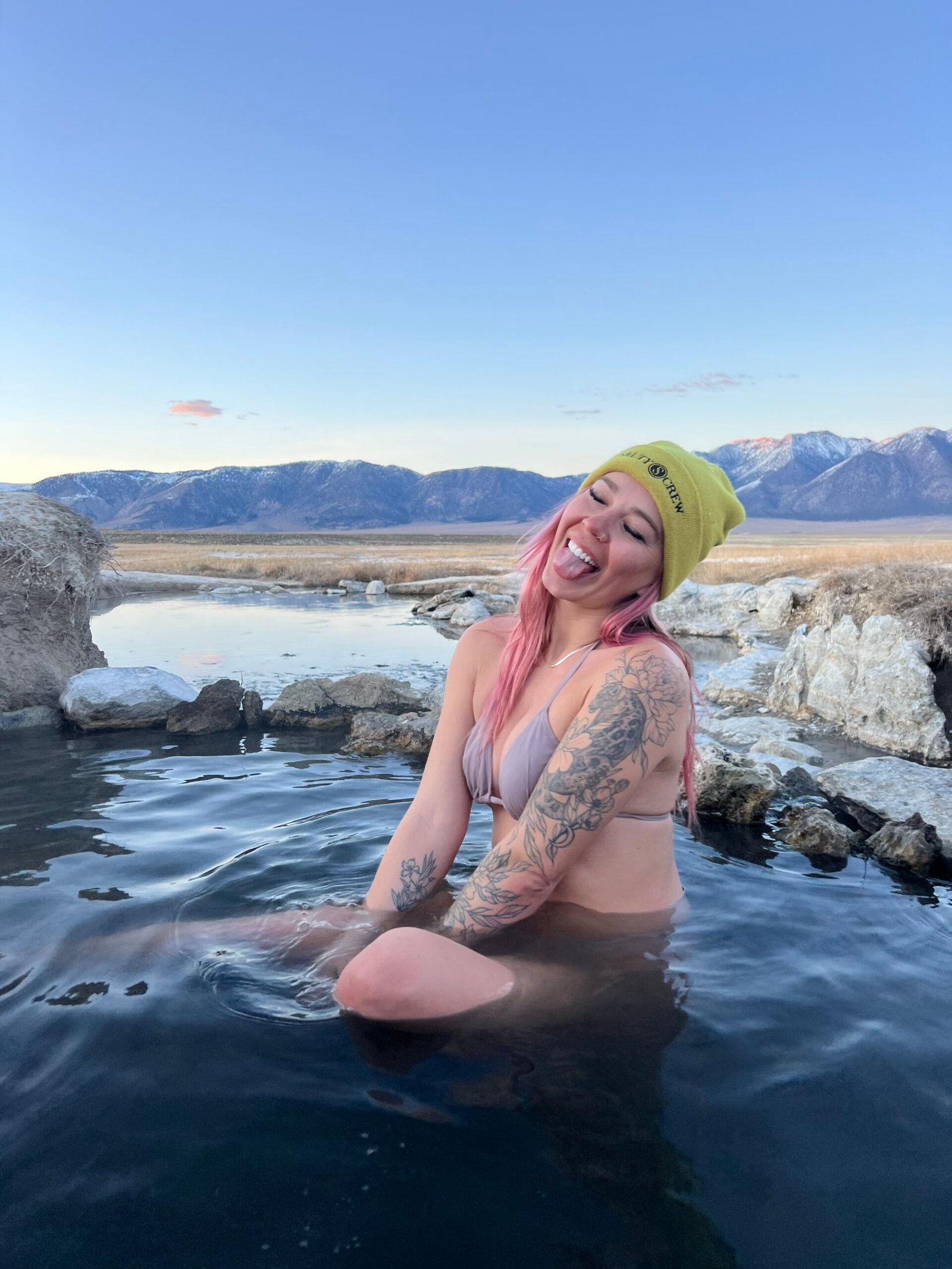 Me in a green beanie soaking in a hot spring with the Eastern Sierra behind