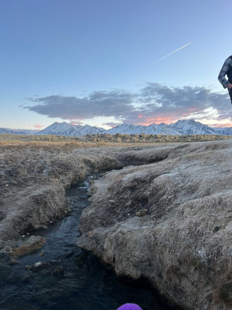 Hot spring channel winding through the sagebrush with the Sierra behind