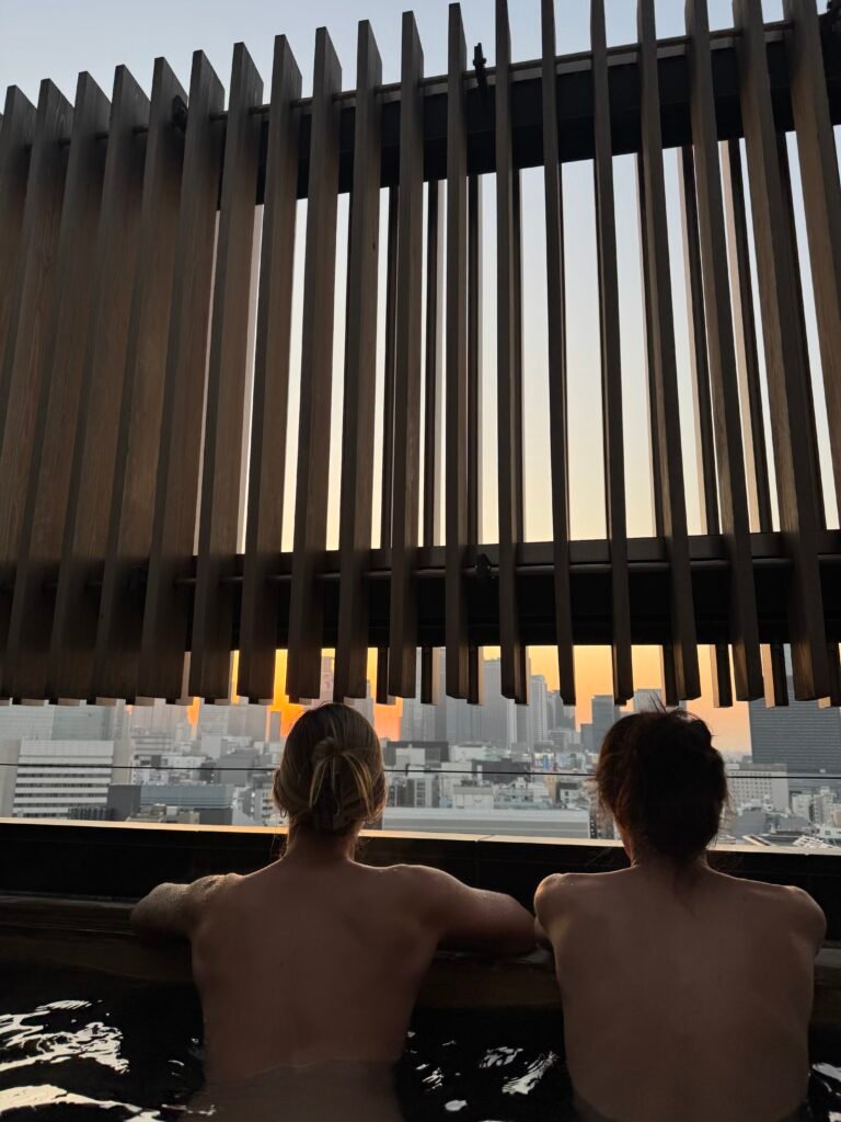 Two friends soaking in the rooftop onsen looking out over Tokyo