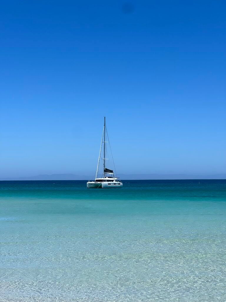 A sailboat anchored in turquoise water off El Tecolote