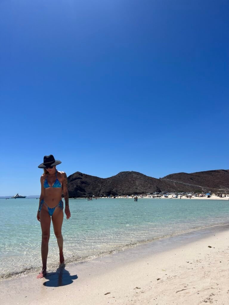 Me standing on the white sand at Balandra Beach with the shallow turquoise bay behind me