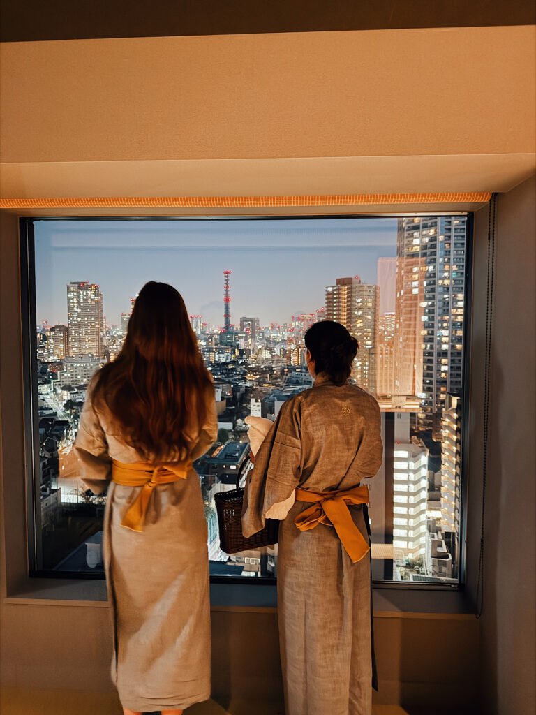 Two friends in robes looking out the window at Tokyo